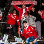 Grupo de torcedores do Internacional com camisas e casacos vermelhos exibindo um cachecol do clube à noite, nos arredores do Estádio Beira-Rio, antes de jogo da Libertadores de 2015