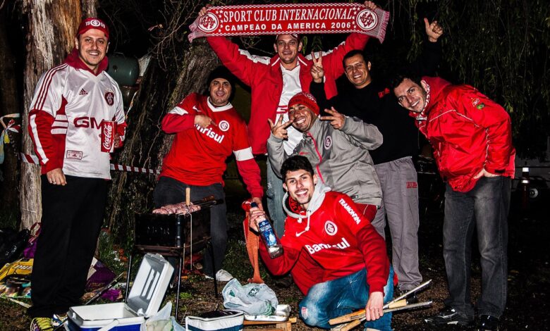 Grupo de torcedores do Internacional com camisas e casacos vermelhos exibindo um cachecol do clube à noite, nos arredores do Estádio Beira-Rio, antes de jogo da Libertadores de 2015