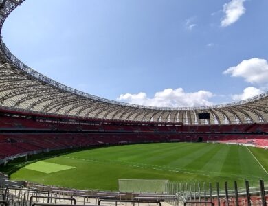 Vista interna do Estádio Beira-Rio vazio em 2024, com gramado, cadeiras vermelhas e a cobertura circular aberta para o céu azul