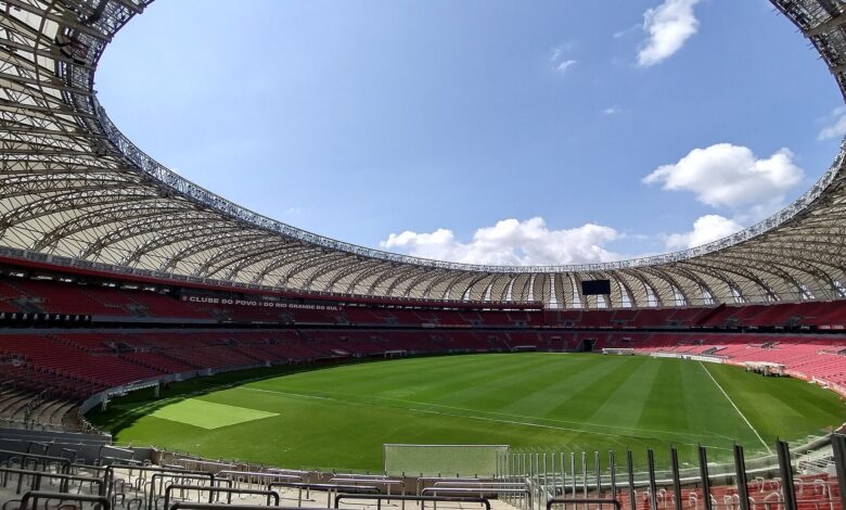 Vista interna do Estádio Beira-Rio vazio em 2024, com gramado, cadeiras vermelhas e a cobertura circular aberta para o céu azul